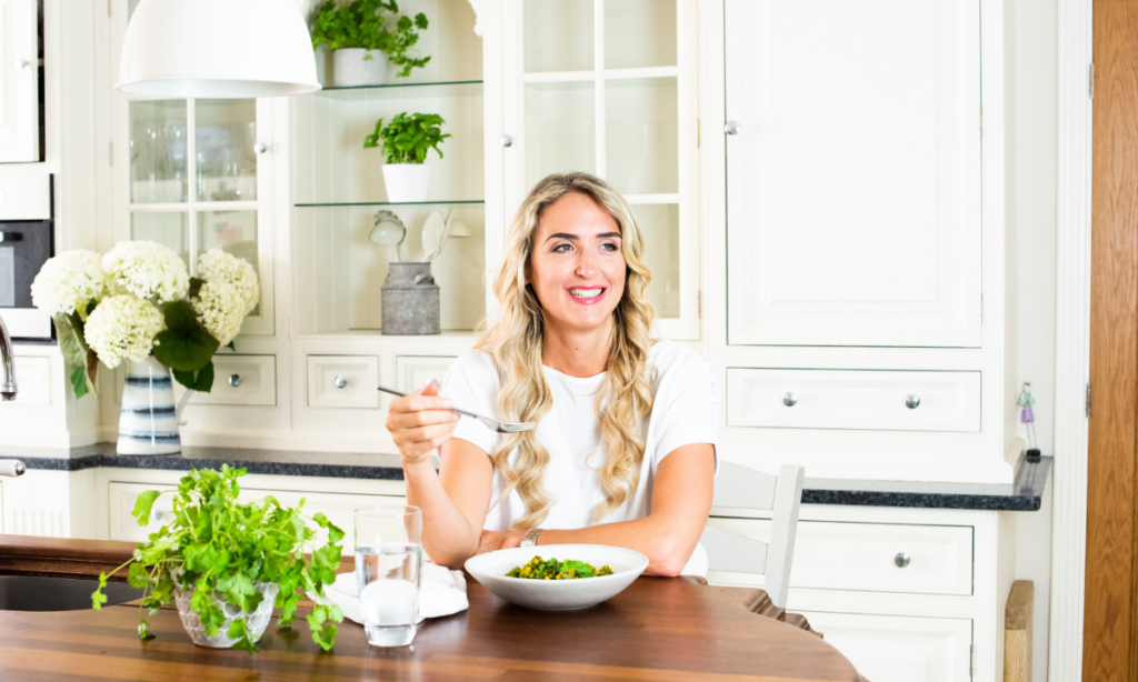 Charlotte Grand sitting in a bright, modern kitchen enjoying a healthy meal, representing a fertility-focused healthy lifestyle