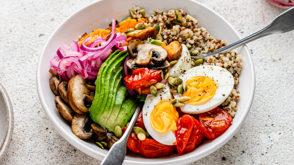 Fertility-boosting meal with quinoa, avocado, boiled eggs, roasted tomatoes, mushrooms, and pumpkin seeds for stable blood sugar.