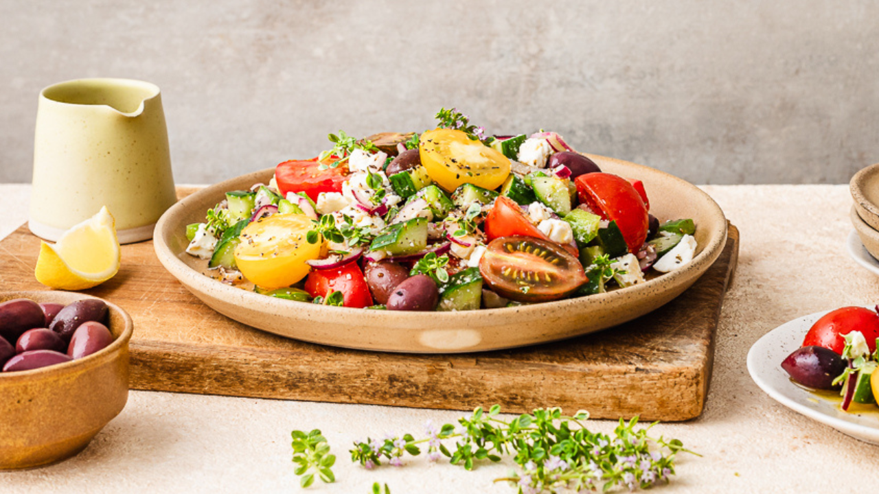 Mediterranean fertility salad with cherry tomatoes, cucumber, olives, feta, and fresh herbs, served on a rustic plate for blood sugar balance.