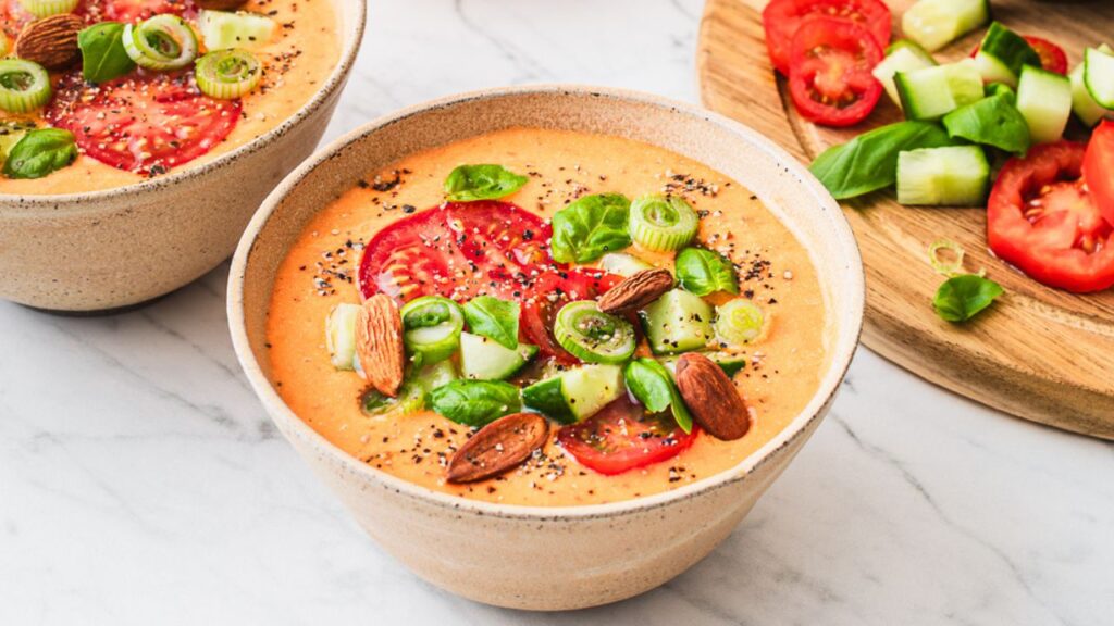 A bowl of creamy tomato soup topped with fresh tomatoes, cucumber, almonds, and basil: A top food source of carotenoids like lycopene to improve sperm quality and motility.