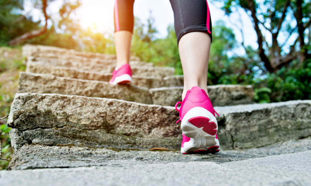 Close-up of a woman’s legs and feet walking up stone steps in nature, symbolising healthy movement and an active lifestyle for fertility support