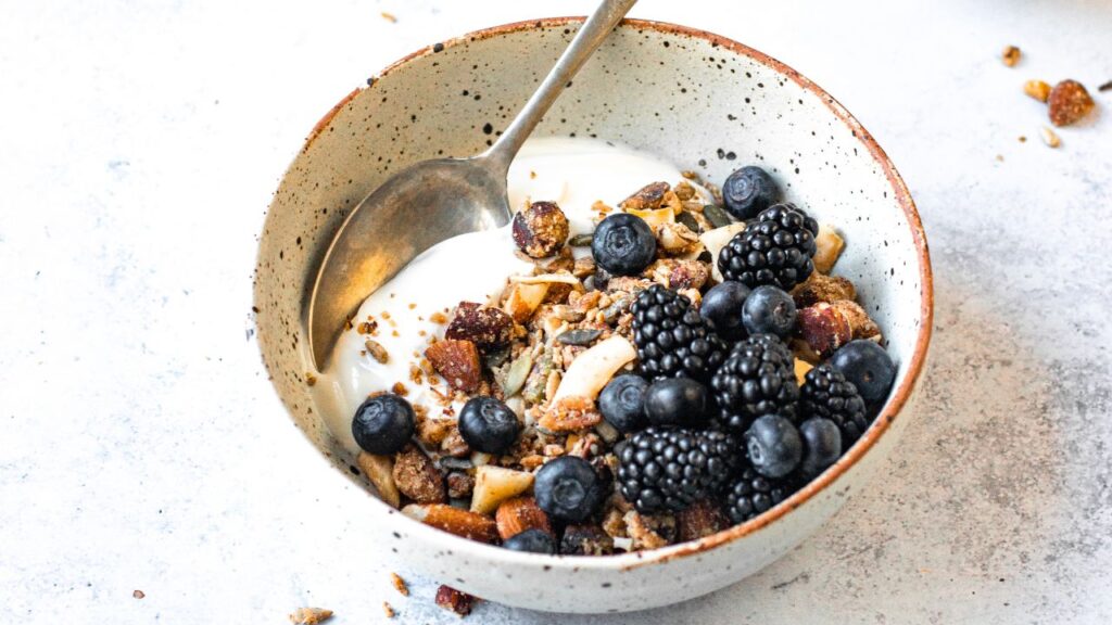 Protein-rich fertility breakfast featuring homemade nutty granola with Greek yoghurt, blackberries, and blueberries. A nutrient-dense, high-protein meal packed with healthy fats, fibre, and antioxidants to support hormone balance and reproductive health.